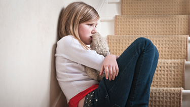 Sad girl holding stuffed animal.